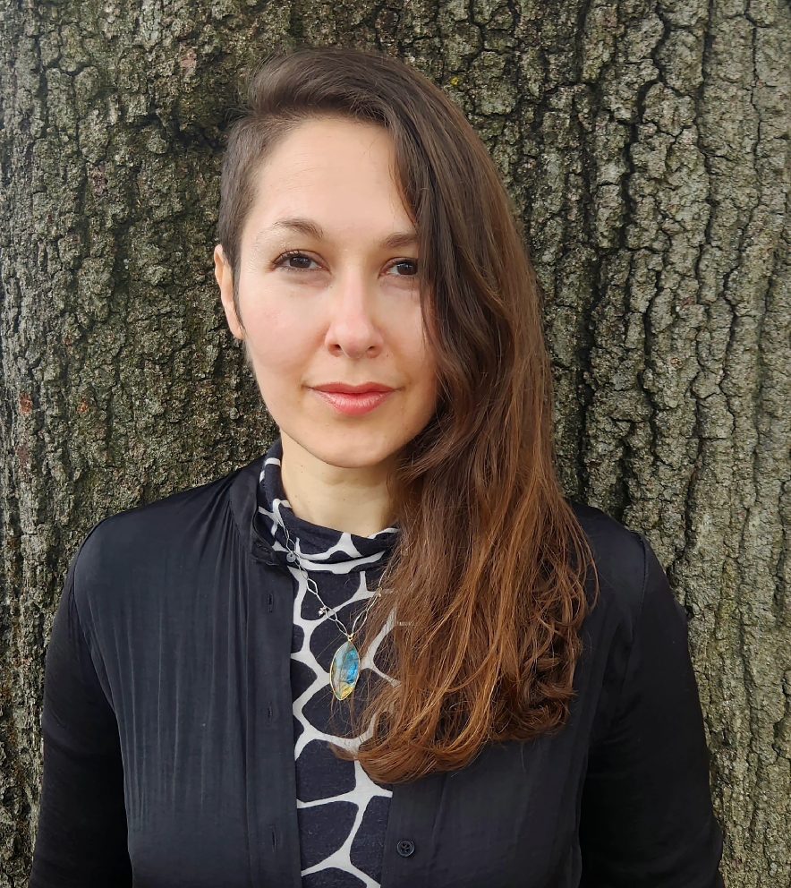 Headshot of artist Marina Tsaplina standing against a tree.