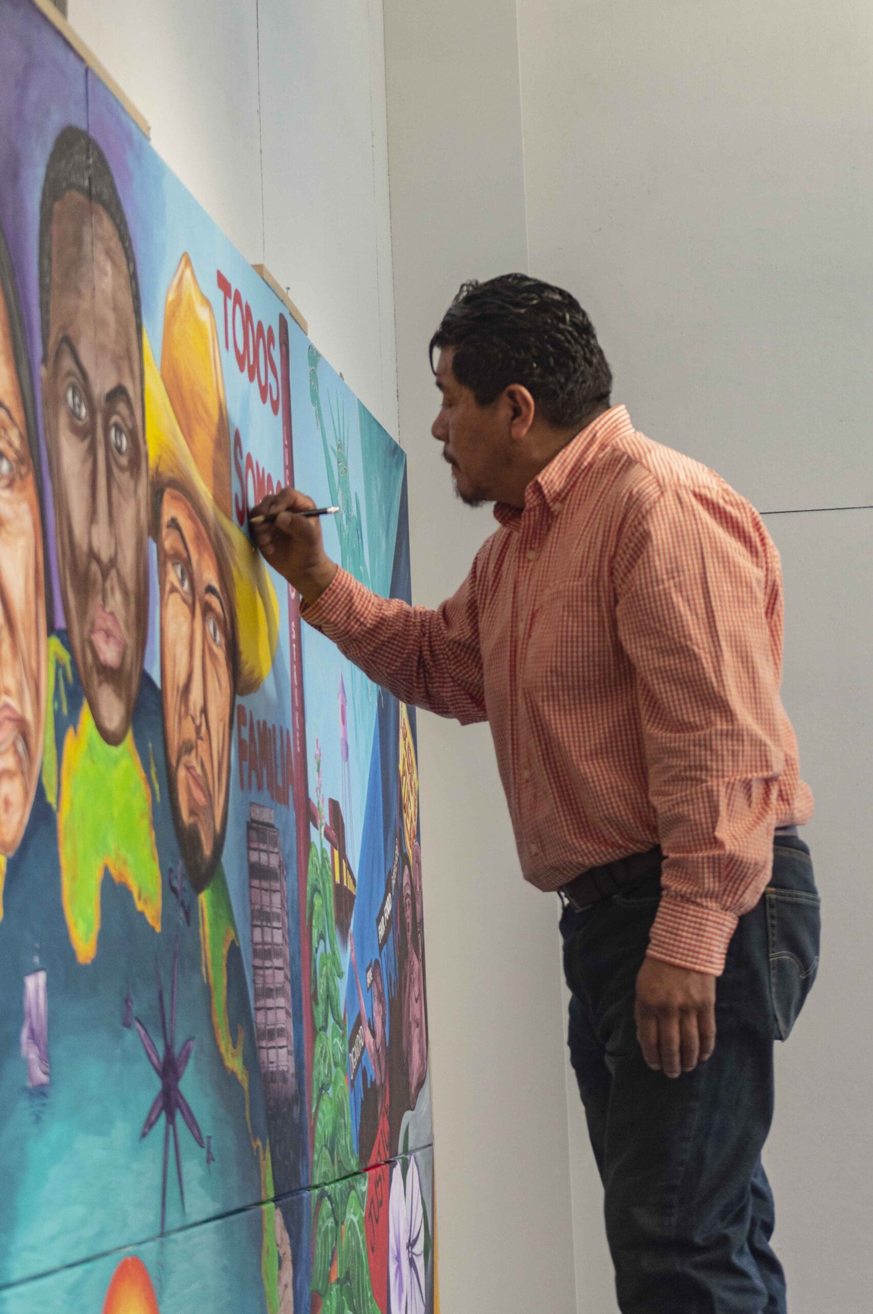 Man standing next to canvas in profile with brush raised.