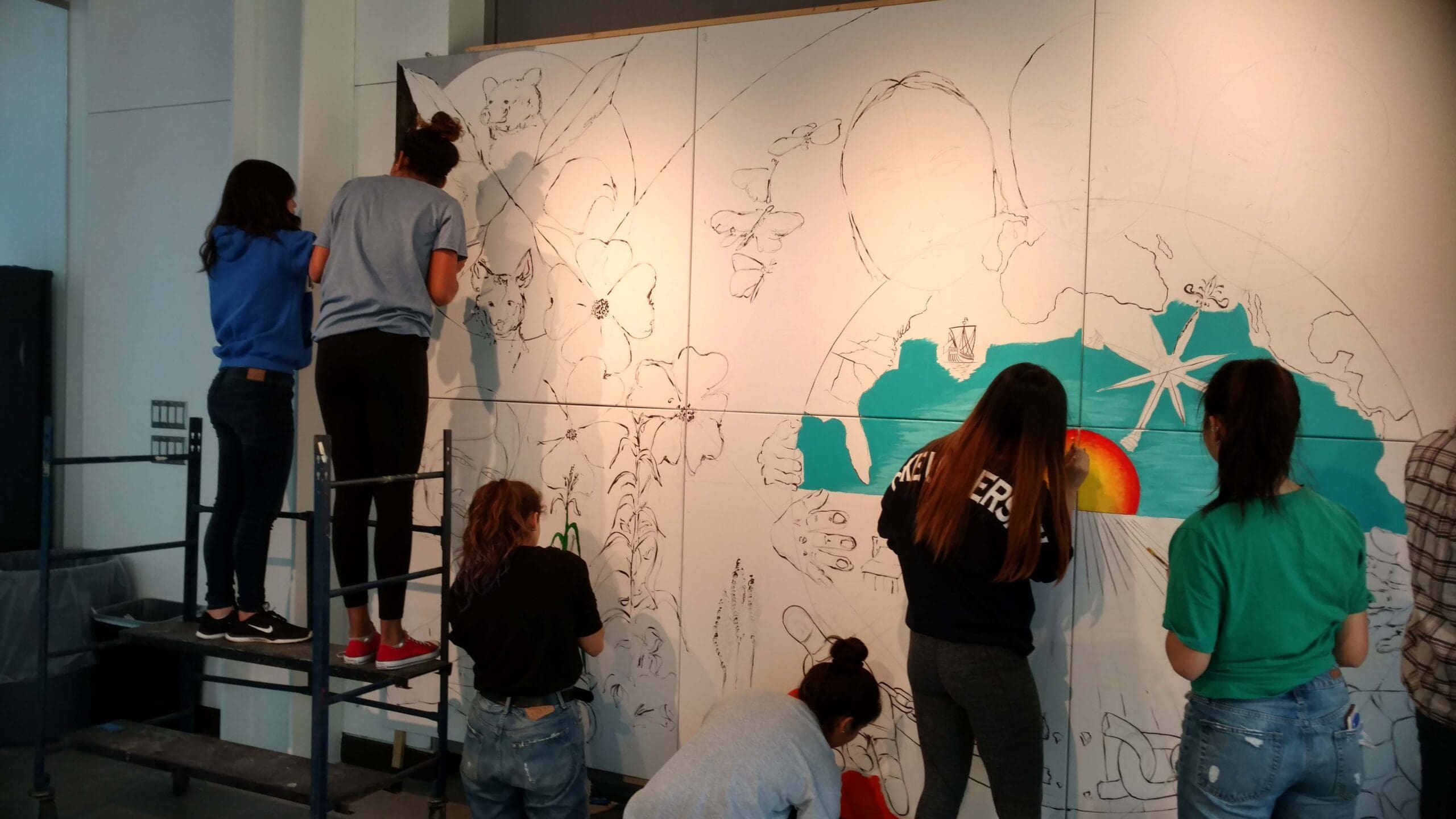 Students painting mural, much of it blank.