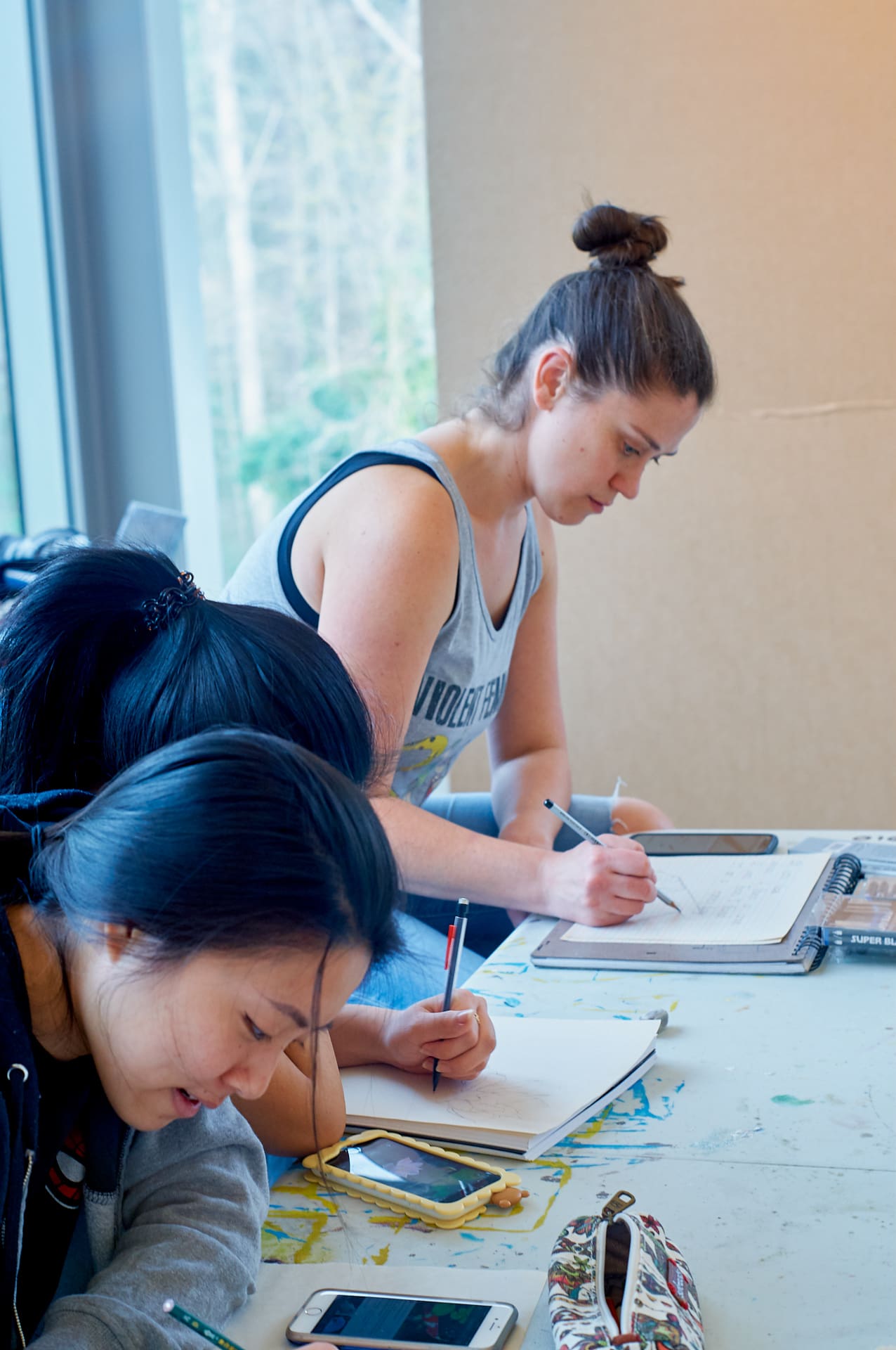 Students seated at a table and drawing