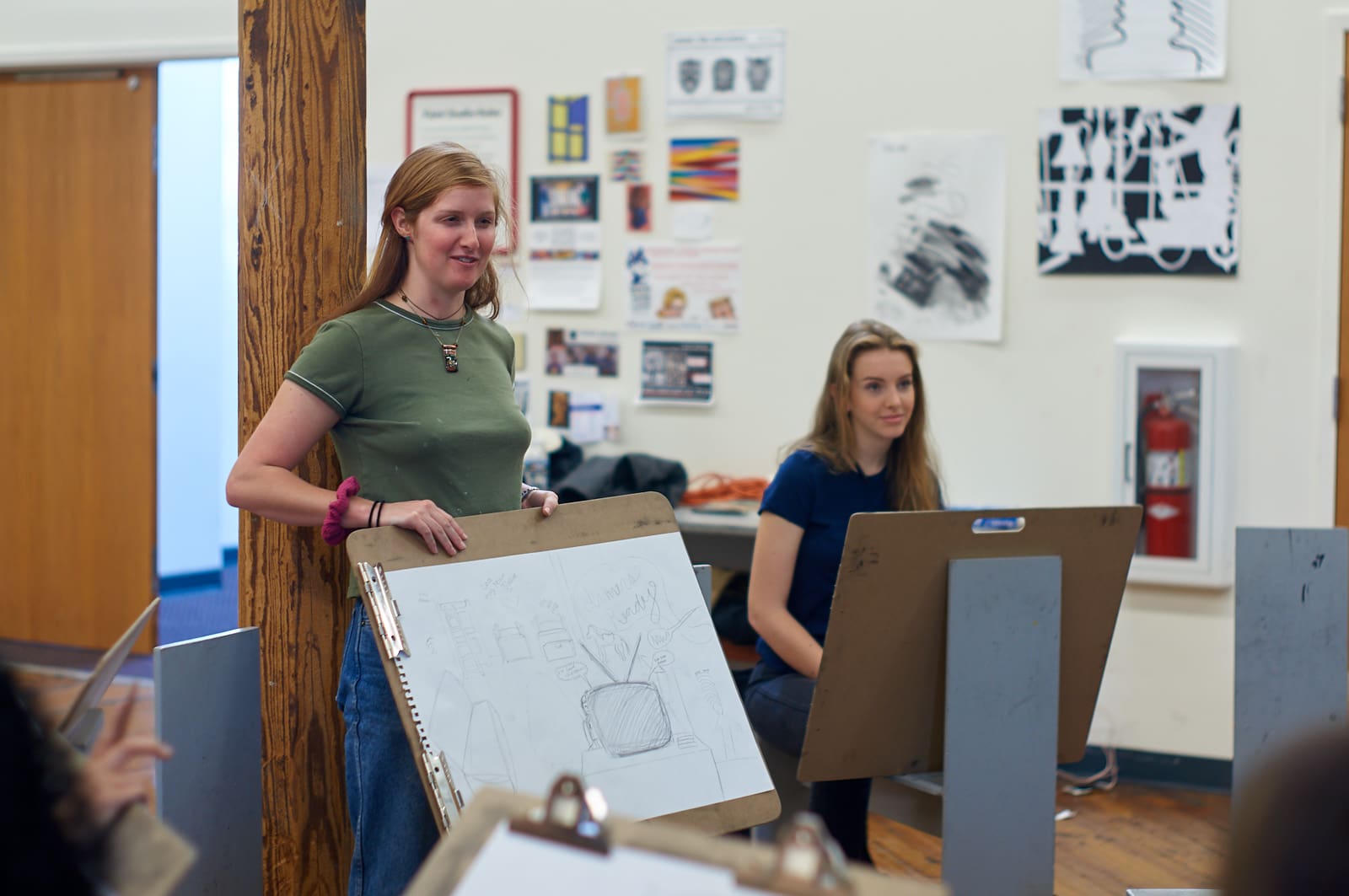 A student presents her drawing of the first room she remembers to the class