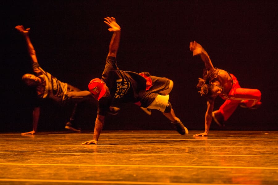 Three Rennie Harris dancers on stage, spinning with one hand on floor