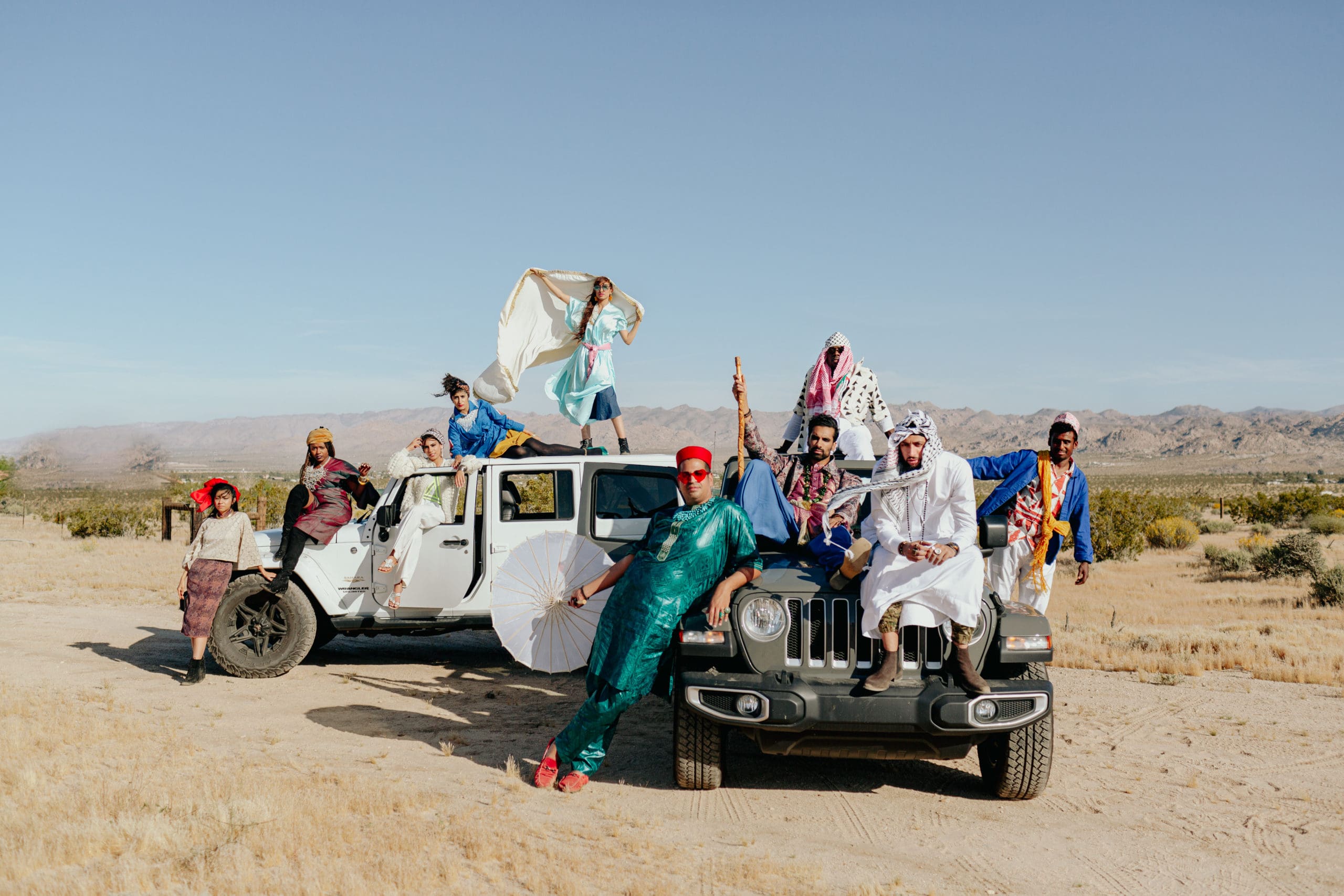 A group of people posing on cars in the desert