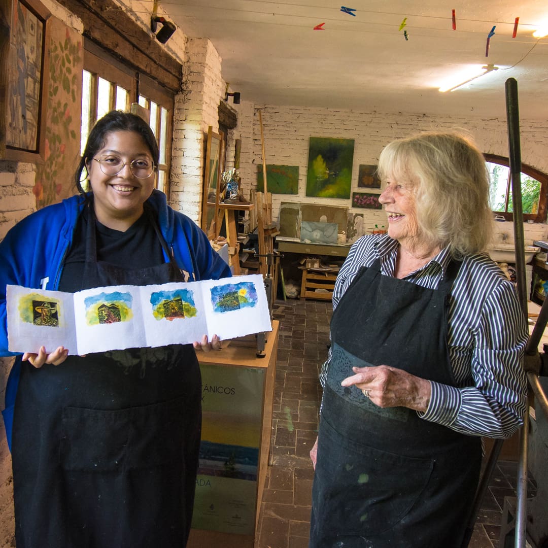 A young adult women holding a foldout print standing next to a women in a print shop