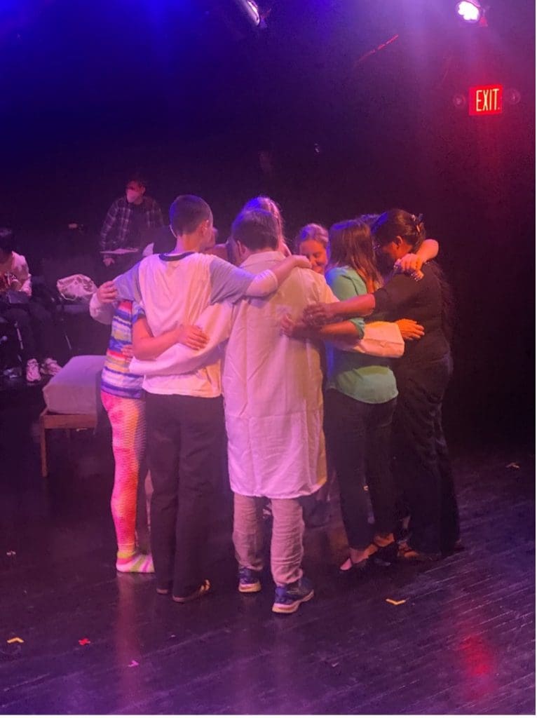 A group of young adult students hugging on stage