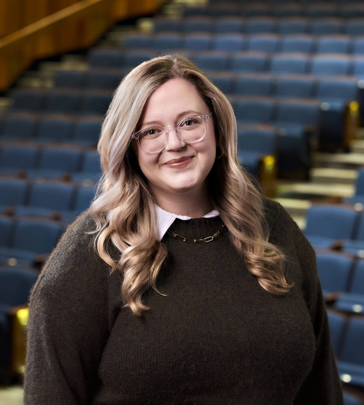 Woman with blonde hair in front of empty theater seats