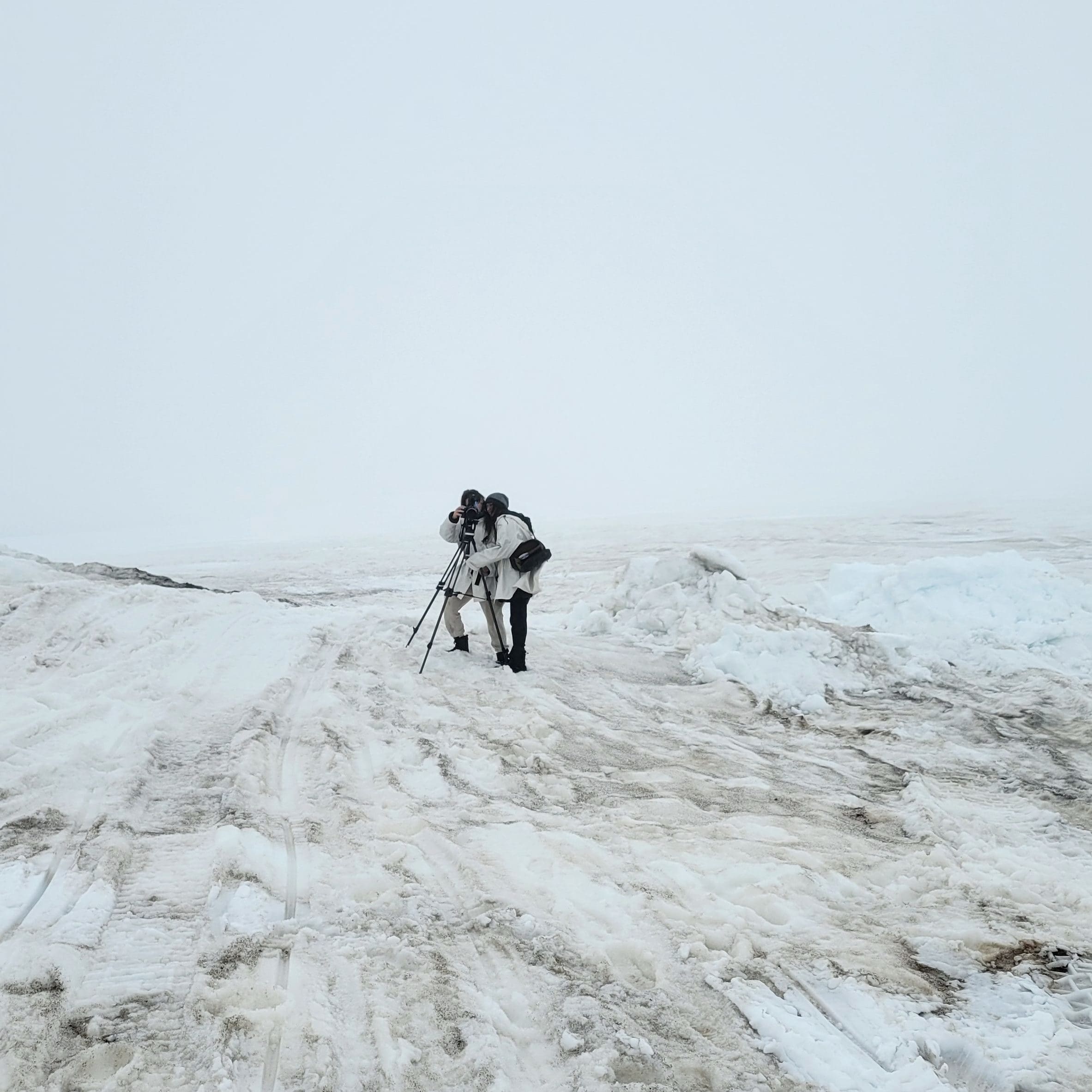 Two people wearing snow gear outside standing on snow and ice