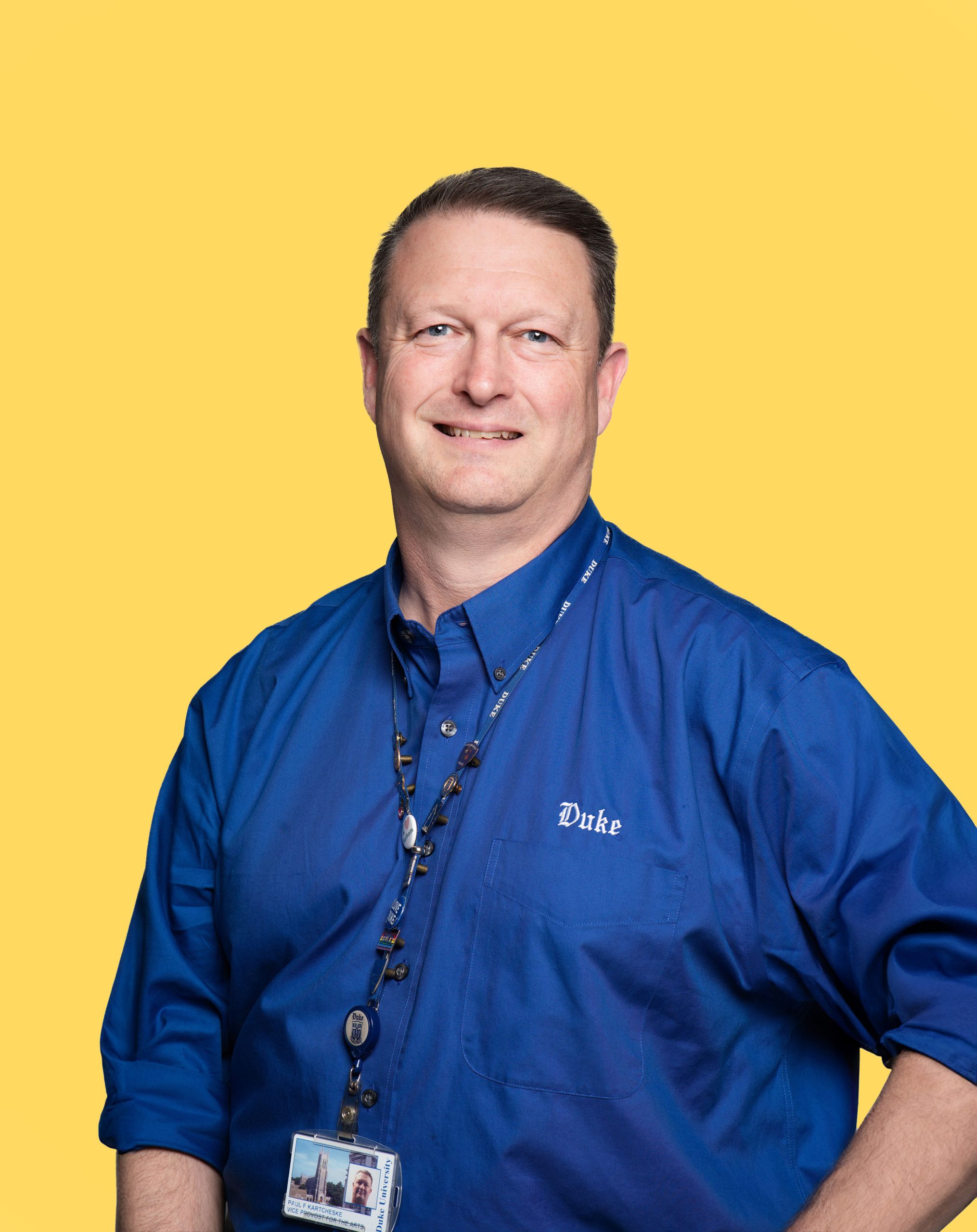 A man with short brown hair in a bright navy blue button up.