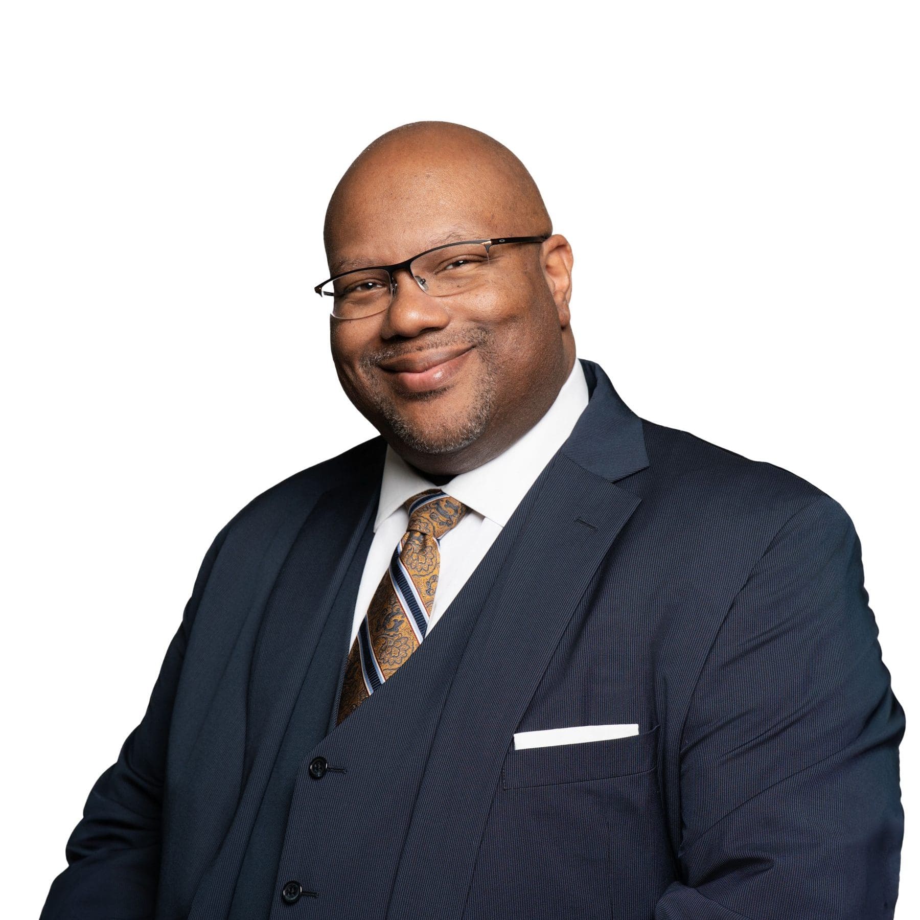 A man wearing a navy suit and stripped tie, with a warm smile on his face.