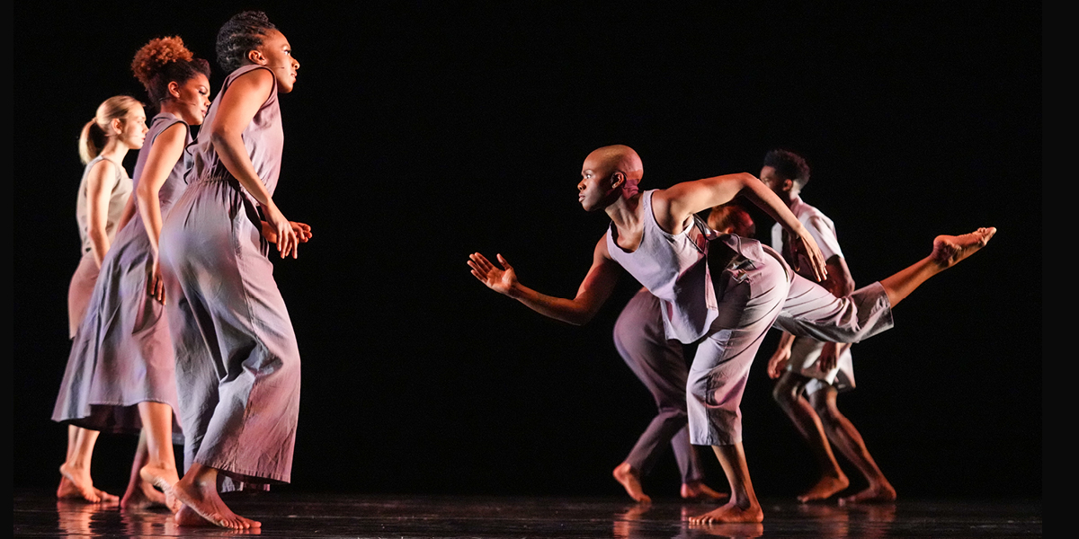 A captivating performance unfolds as dancers take the stage, their movements highlighted in a dimly lit room.