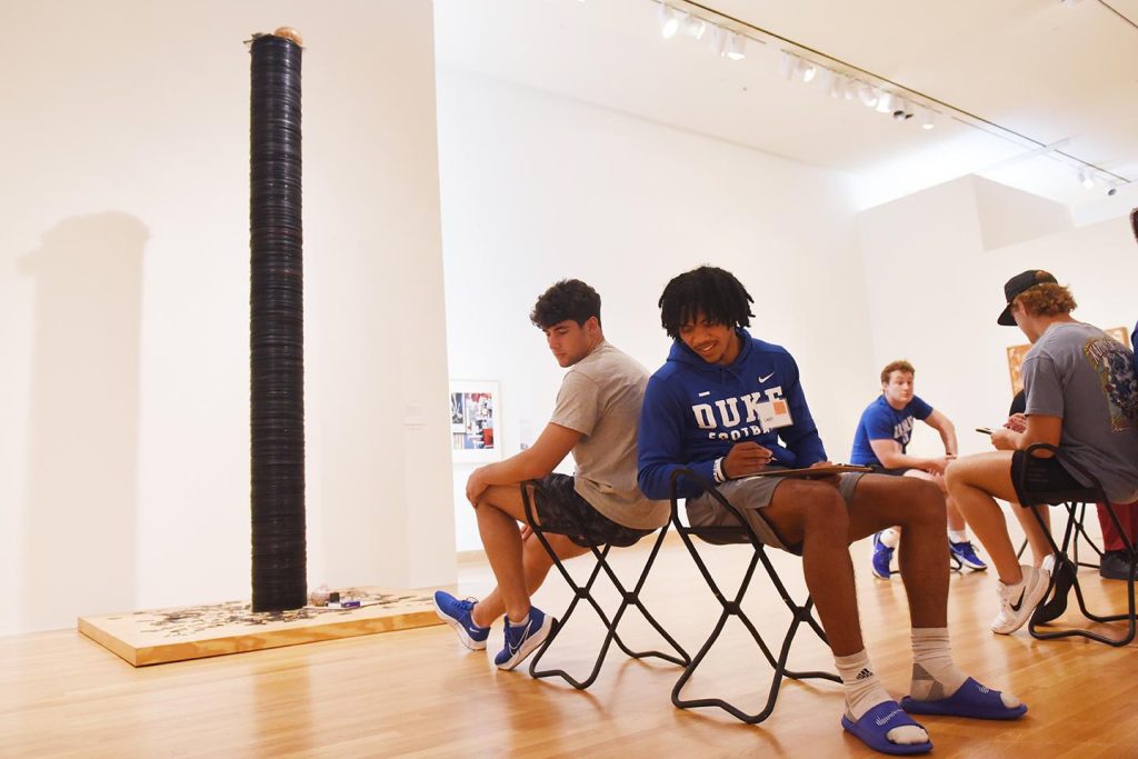 Duke student football players participate in the "Back to Back Drawing" activity