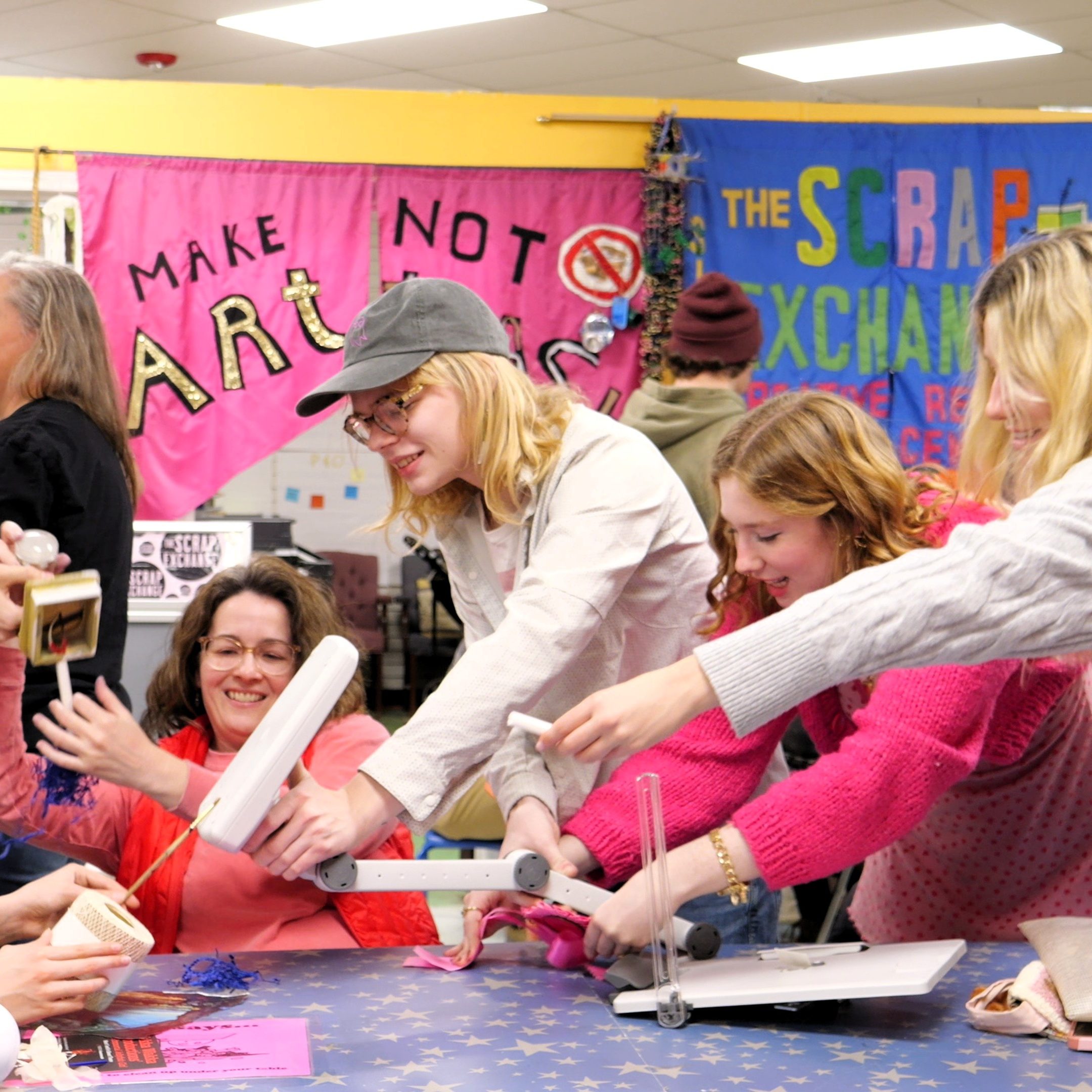 A mix of young adults, adults, and children working on building a puppet.