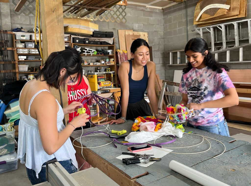 Three young adult women working on a hands-on project in a studio